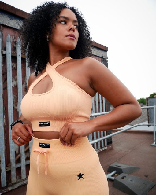 lady wearing poweer x purpose cross bra peach vibe set