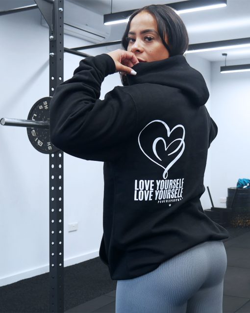 pretty girl at the gym squat rack wearing power x purpose love yourself hoodie